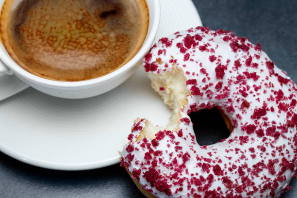 A cup of coffee and a bitten donut