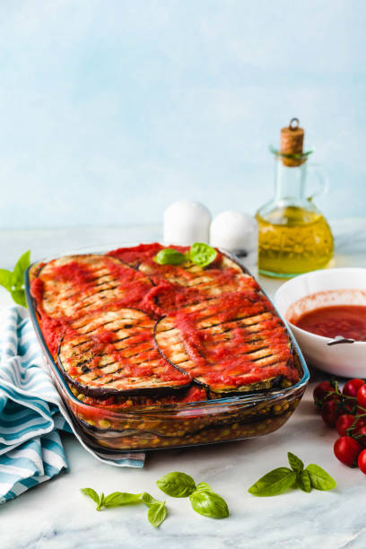 Vegan Eggplant Parmigiana made of peas and lentils and fresh tomatoes on a marble kitchen table. Healthy comfort recipe for the whole family