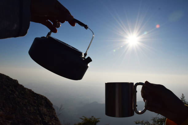 istock Silhouette kettle and cup at sunrise with mountain background 1064679056