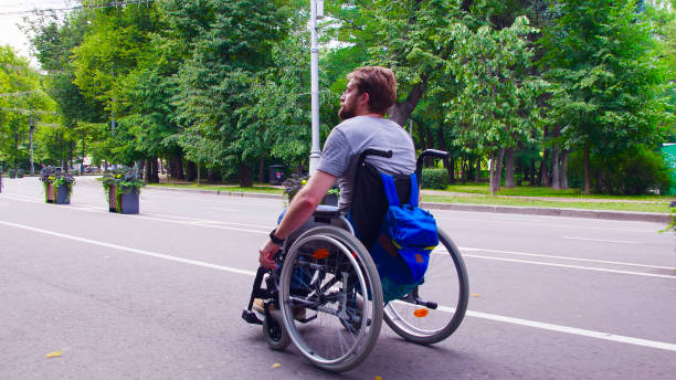 istock Young disable man walking in the park in wheelchair 1064679498
