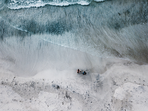 Aerial view of couple with dog walking at Kvalvika beach on Lofoten Islands in Norway