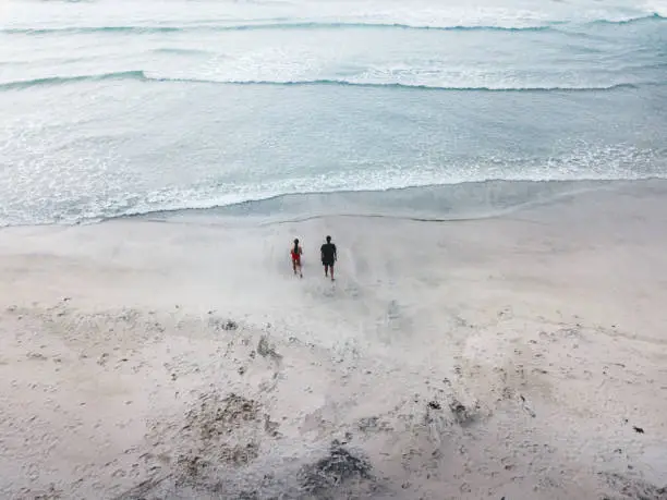 Photo of Aerial view of couple with dog walking at Kvalvika beach on Lofoten Islands in Norway