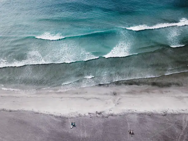 Photo of Aerial view of couple with dog walking at Kvalvika beach on Lofoten Islands in Norway