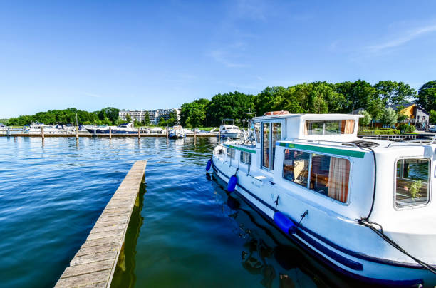 Houseboats and yachts are moored in Goehren-Lebbin (Germany) at a jetty of the lake Fleesensee Houseboats and yachts are moored in Goehren-Lebbin (Germany) at a jetty of the lake Fleesensee houseboat photos stock pictures, royalty-free photos & images