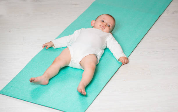 dziecko wykonuje ćwiczenia fizyczne na macie do jogi. joga dla niemowląt - male body sport exercising zdjęcia i obrazy z banku zdjęć