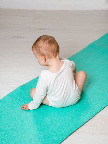 dziecko wykonuje ćwiczenia fizyczne na macie do jogi. joga dla niemowląt - male body sport exercising zdjęcia i obrazy z banku zdjęć