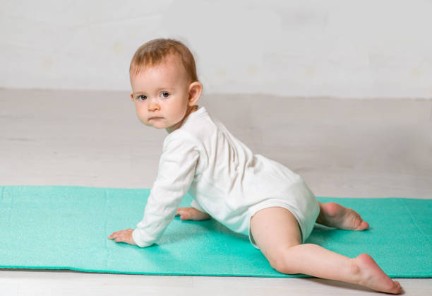 dziecko wykonuje ćwiczenia fizyczne na macie do jogi. joga dla niemowląt - male body sport exercising zdjęcia i obrazy z banku zdjęć