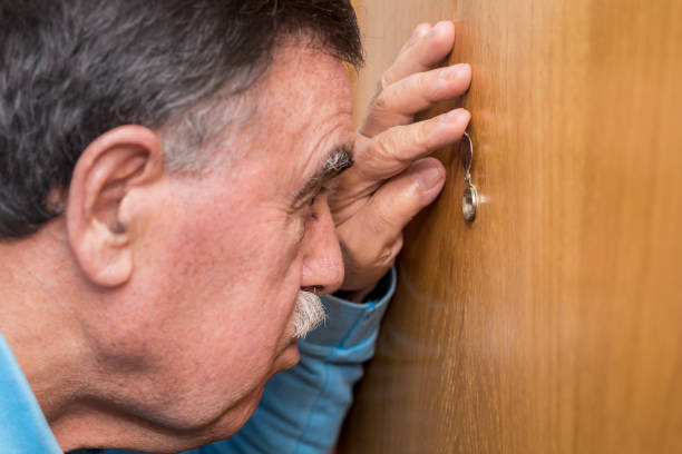 Senior man looking through peephole Senior man looking through peephole peep hole stock pictures, royalty-free photos & images