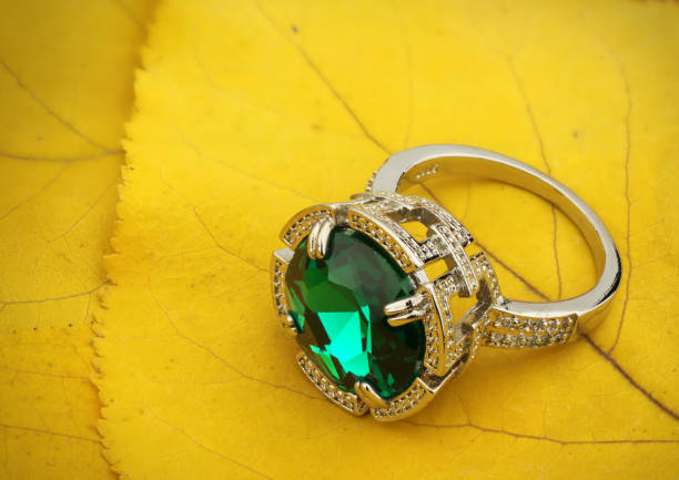 Vintage emerald ring on green satin as a background