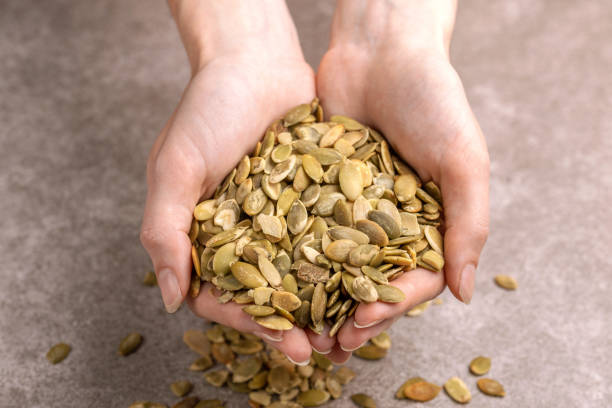 istock Fresh pumpkin seeds in woman's hands. Marble background 1064718136