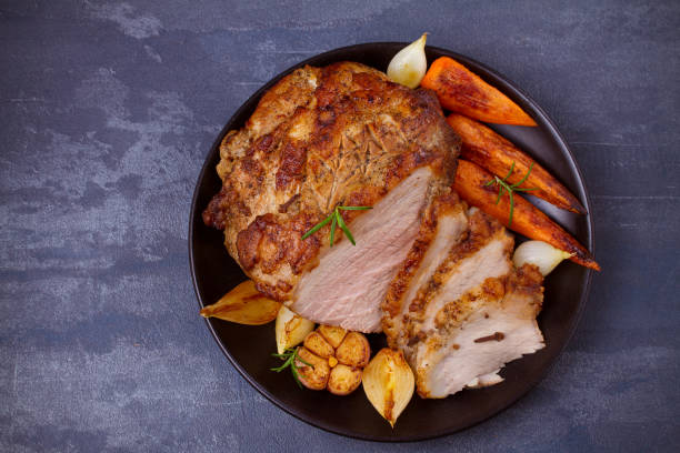 istock Baked ham with vegetables: carrots, onions, garlic and herbs 1064718830