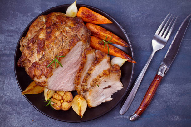 istock Baked ham with vegetables: carrots, onions, garlic and herbs 1064719980