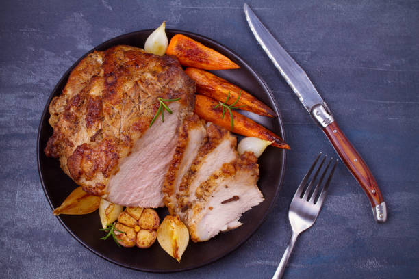 istock Baked ham with vegetables: carrots, onions, garlic and herbs 1064720026