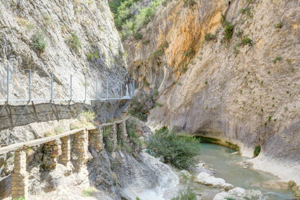 istock The Vero river canyon during a summer day with the hanging elevated path over it, the typical red iron rock and some trees, in Alquezar, Spain 1064723248