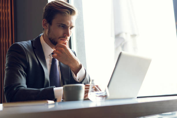 istock Attractive businessman using a laptop and smiling while working in cafe 1064725062