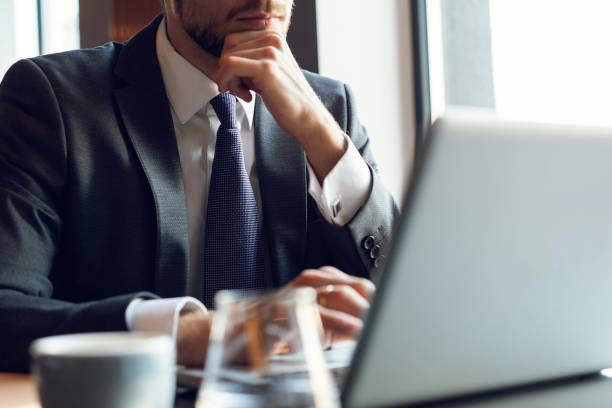 istock Attractive businessman using a laptop and smiling while working in cafe 1064725078