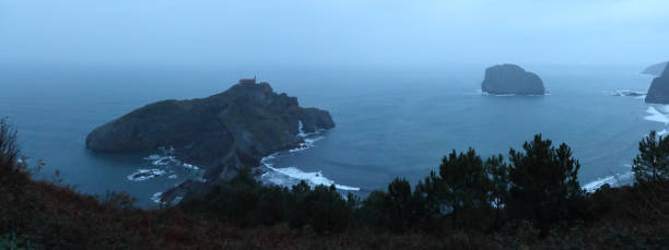 ガルテルガトシェ膵島とバスクの国, スペイン、荒れた海での霧の冬夜の間に岩の風景 - mist rock winter autumn ストックフォトと画像
