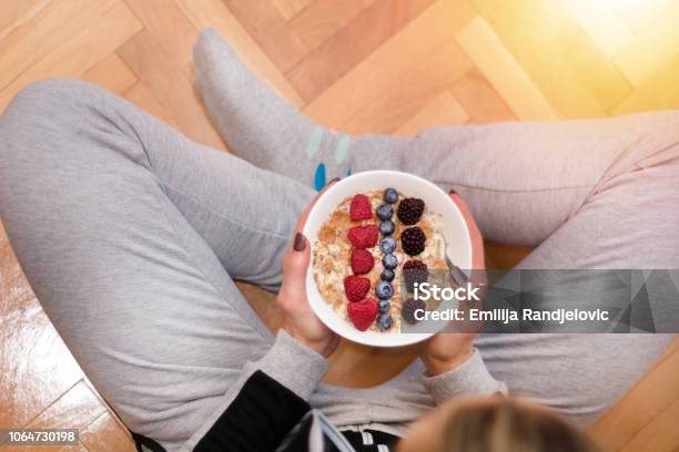 Photo libre de droit de Femme En Vêtements Maison Manger La Bouillie Davoine Dans Un Bol Orné De Mûres Framboises Et Bleuets banque d'images et plus d'images libres de droit de Céréales du petit déjeuner