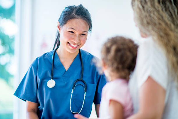 Female doctor with a young girl patient and her mother Female doctor with a stethoscope and scrubs in a medical office with a young girl patient and the mother paediatrician stock pictures, royalty-free photos & images