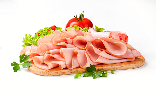 Thinly sliced ham on wooden cutting board