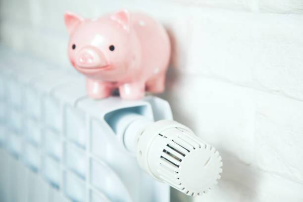 istock Piggy bank on heating radiator with temperature regulator 1064736104