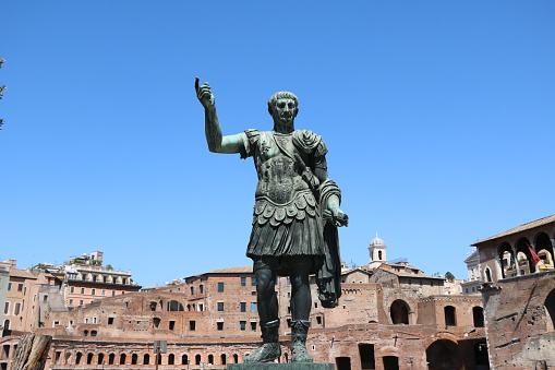 A bronze statue of a Roman Emperor pointing towards the sky, located on Via dei Fori Imperiali by the Roman Forum in central Rome.