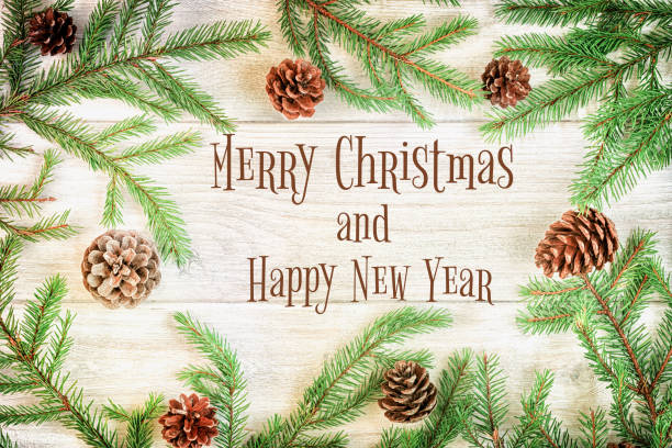 istock Christmas composition, frame. Spruce branches with cones, laid out in a circle. In the center is the inscription Merry Christmas and Happy New Year. Festive photo on a light wooden background. 1064743320