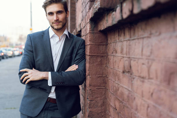 istock Happy young formal dressed man leaning on a wall outdoors 1064744016