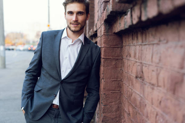 istock Smiling young male manager formal dressed leaning on a wall outdoors. 1064744036