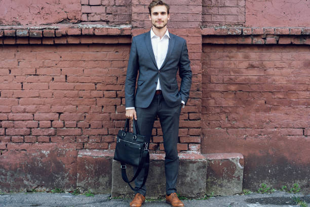 istock Happy young formal dressed man leaning on a wall outdoors 1064744062