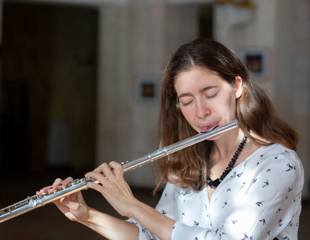 istock A beautiful woman posing while playing on a flute 1064746002