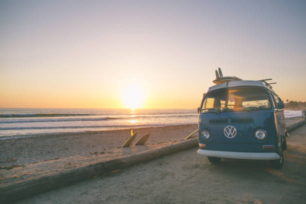 Classic California Surf Culture San Onofre, CA, USA - April 10, 2017:  A current but timeless image of a 60's VW Bus, parked at San Onofre Surf beach.  Single fin classic longboards liter the scenery as the surfers enjoy the waves in the fading light of the day. breaking wave stock pictures, royalty-free photos & images