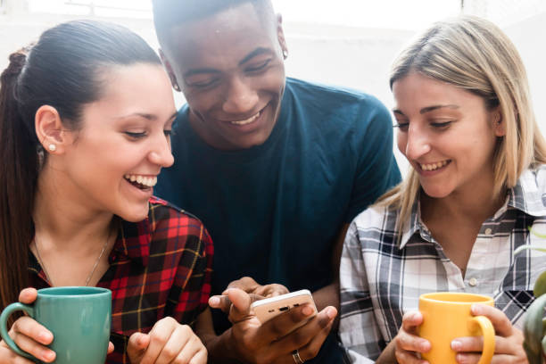 istock Group of friends having fun enjoying a coffee while looking at something on smartphone laughing 1064751080