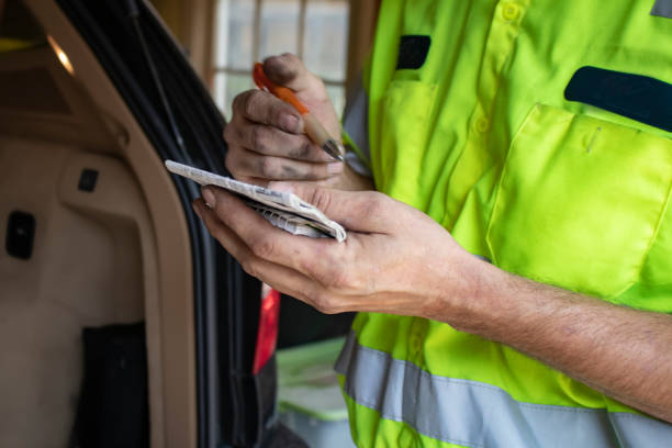 istock Automotive repairman with dirty hands makes notes in a small notebook standing by back of a car with hatchback open - Closeup and selective focus 1064753396
