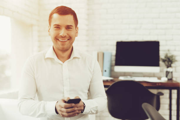 istock Young Smiling Man Is Standing With Smartphone. 1064760754