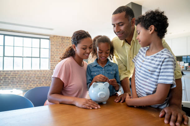 Family saving money in a piggybank Portrait of a happy African American family saving money in a piggybank - home finances concepts london girl stock pictures, royalty-free photos & images