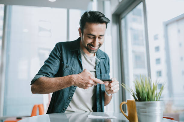 uomo adulto deposita assegno con smartphone - distinta di versamento foto e immagini stock