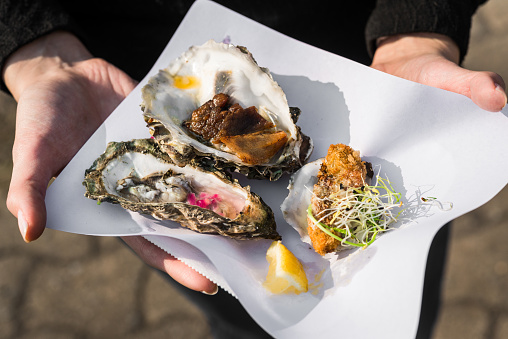 Close up of raw, fried, and smoked gourmet oysters at a street food market fair festival