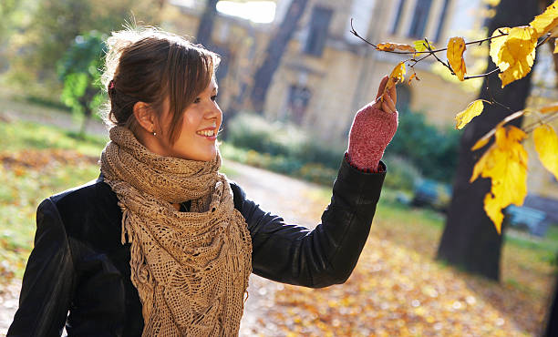 The smiling girl considers autumn leaves stock photo