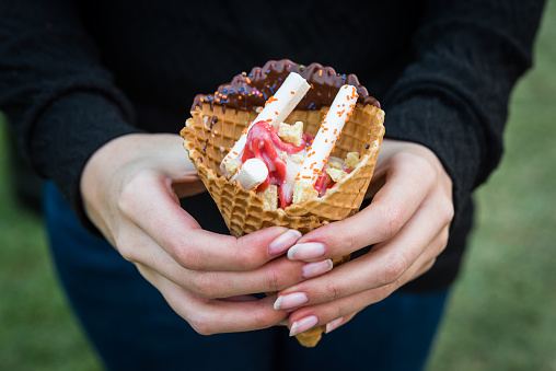 Gourmet tamarillo tomato tree ice cream in a cone with chocolate, sprinkles, and meringues at a street food market fair festival