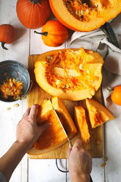 istock Woman's hands chopping pumpkin on cutting board, top view 1064776762