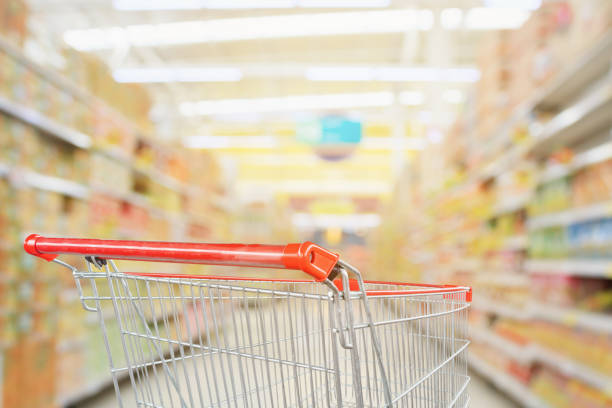 istock Supermarket aisle blurred background with empty red shopping cart 1064785722