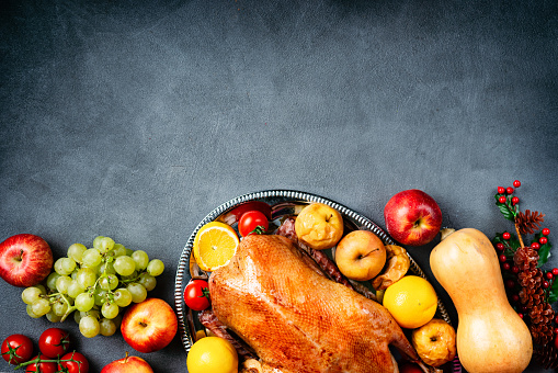 Flat lay of thanksgiving roasted whole goose and vegetables on rustic table. Copy space