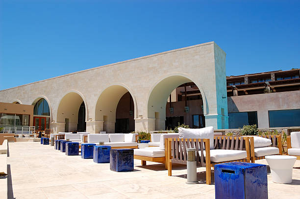 Sithonia, Chalkidiki, Greece. Traditional tavern cafe exterior with wooden table chairs. Olive tree branch focused in front with the view of the aegean sea in the background..