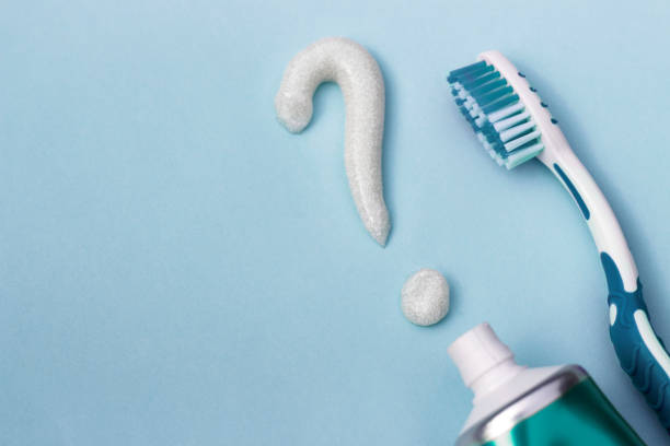 punto interrogativo da dentifricio e spazzolino da denti su sfondo blu, concetto di selezione dentifricio - toothpaste glue blue white foto e immagini stock