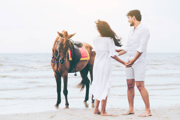 istock Young couple goes horse riding on tropical beach. 1064837076