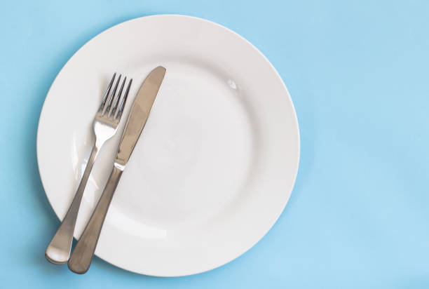 istock Dinner plate, knife and fork isolated on blue backgroud 1064841412