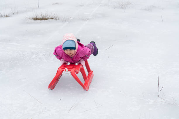 kleines mädchen genießt den schnee - little boys sled clothing slide stock-fotos und bilder