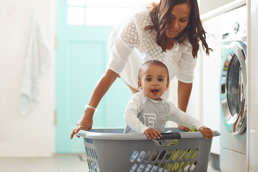 Shot of a mother and her adorable baby boy doing the laundry at home