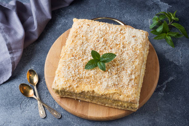 istock Layered cake with cream Napoleon millefeuille vanilla slice with mint on dark background. 1064868350